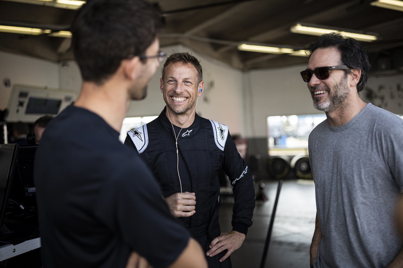 DAYTONA BEACH, FLORIDA - JANUARY 31: Jenson Button talks to Jordan Taylor (L) and Jimmie Johnson (R) in the garage during the NASCAR Garage 56 Test at Daytona International Speedway on January 31, 2023 in Daytona Beach, Florida